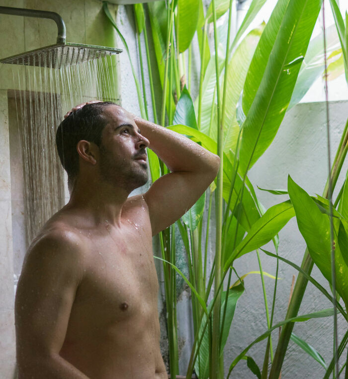 Man enjoying a refreshing shower surrounded by greenery, exemplifying non-sexual attraction.