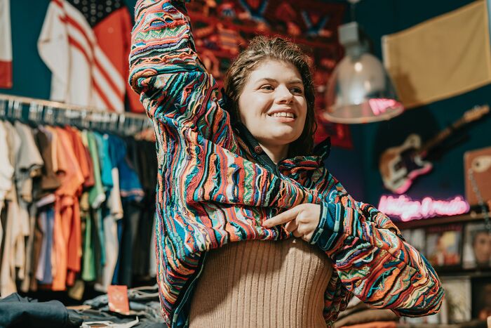 Person trying on a colorful sweater. 