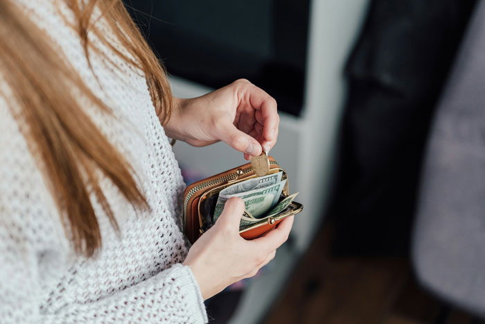 A babysitter holding a wallet, counting money after a last-minute favor.