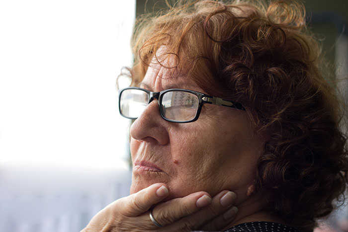 Elderly woman with glasses looking thoughtful, emphasizing respect and relationship boundaries in family settings.