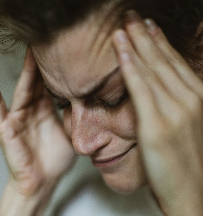 Person holding head, appearing stressed, with furrowed brow, highlighting respect for rules in relationships.