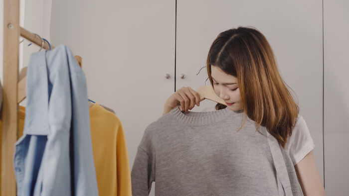 Woman assessing a gray sweater.