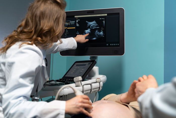 Doctor performing an ultrasound, displaying fetus image on screen, highlighting bereavement support in miscarriage cases.