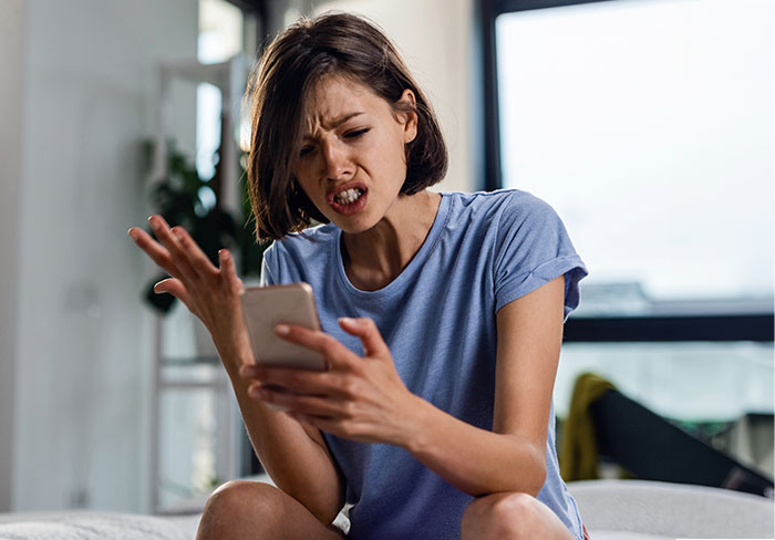 Woman reacting with surprise while reading a message on her phone, expressing frustration at a love confession.