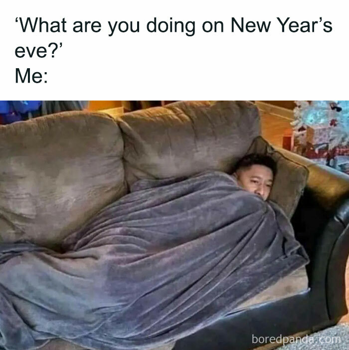 Person bundled in a blanket on a couch, embodying introvert vibes for New Year's Eve.