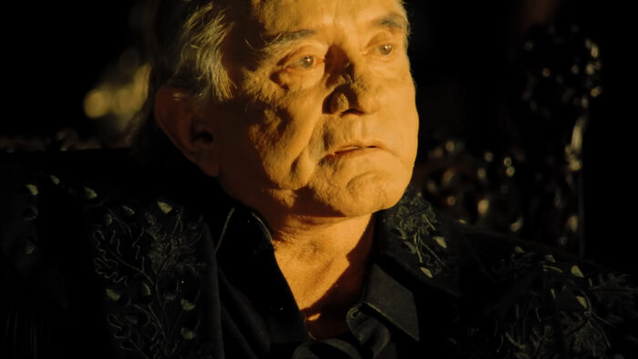 Elderly man in dim lighting, deep in thought, evoking an emotional scene, perfect for tear-jerking movie moments.