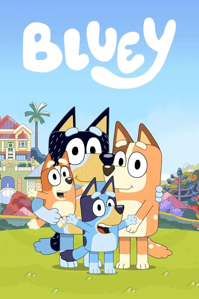 A joyful family of animated dogs from the show Bluey stands together outside their colorful house.