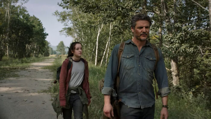 Man and girl walking through a forest, discussing tear-jerking movies, backpacks on their shoulders.