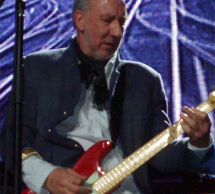 Musician playing electric guitar on stage, lights creating an atmospheric mood, linked to celebrity secrets and scandals.