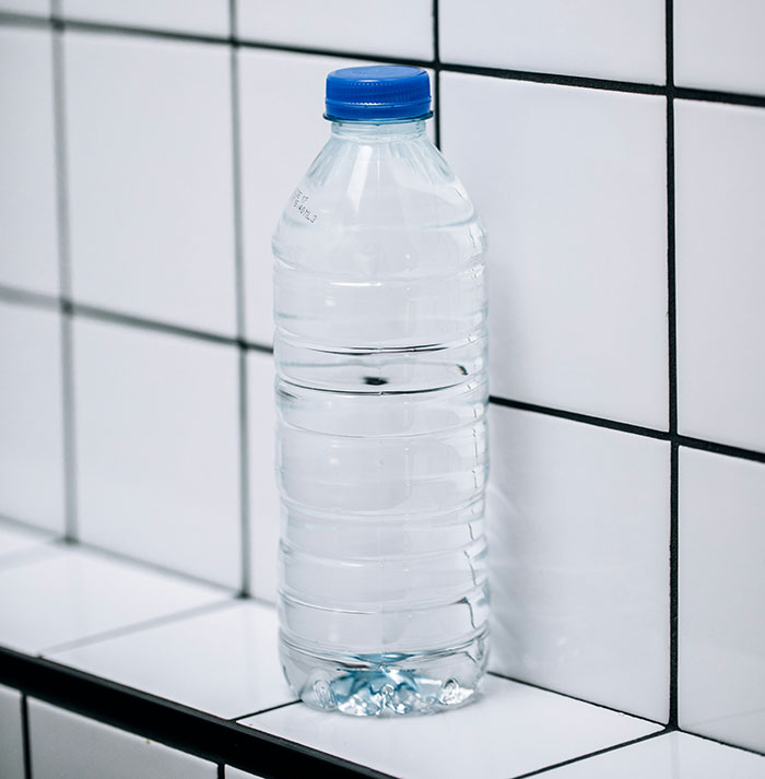 Plastic water bottle with blue cap on a tiled surface, highlighting common scams in America.