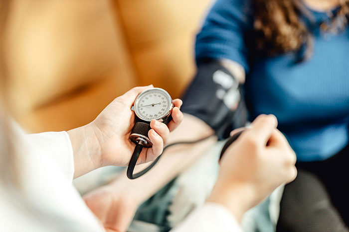 Person measuring blood pressure with a sphygmomanometer, focusing on health care practices in America.