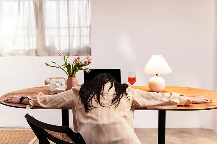 Person overwhelmed at a desk, illustrating stress from common scams in America.