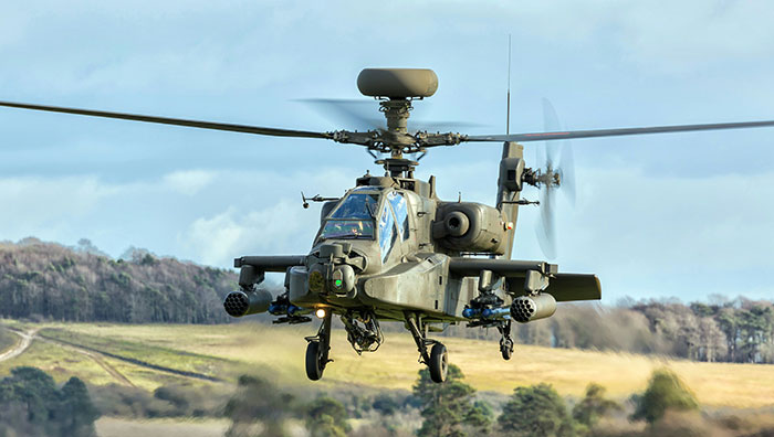 Military helicopter flying over a rural landscape, highlighting potential scams in America.