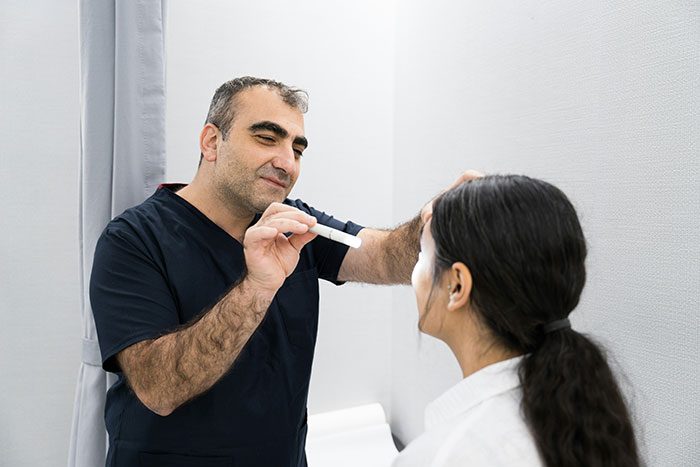 Person in a clinic room, wearing dark scrubs, examining a patient, illustrating common scams in America involving healthcare.