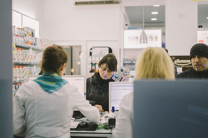 Pharmacy employees interacting with customers, a common setting for scams in America.