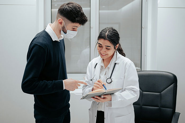 Person wearing a mask talking to a doctor, highlighting common scams in America.