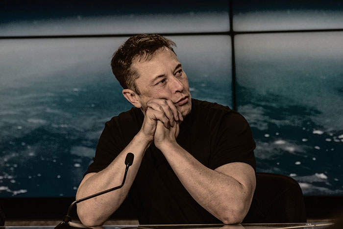 A man in a black shirt sitting at a microphone, relevant to common scams in America.