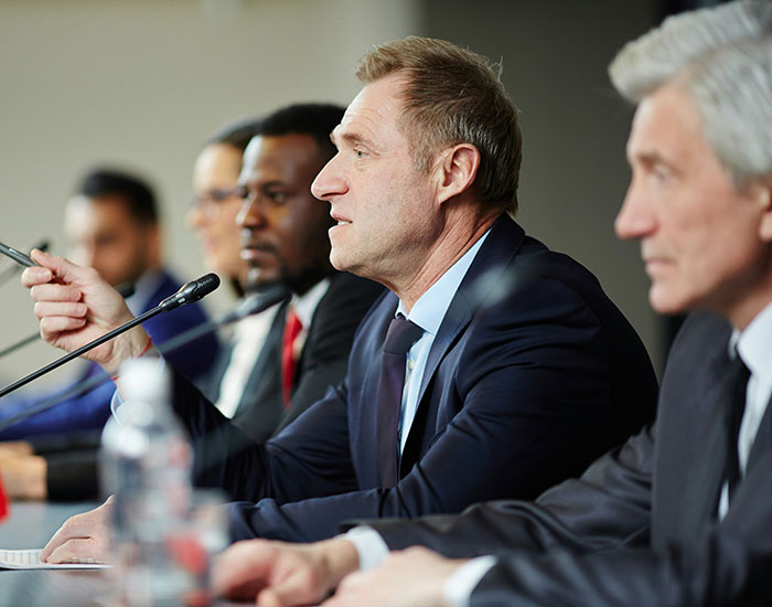 A group of businessmen in suits discussing common scams in America at a conference table.