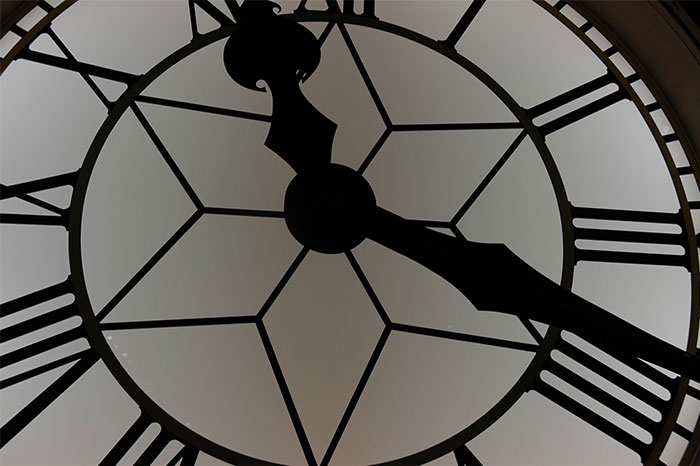 Close-up of clock face representing wasted time and money.