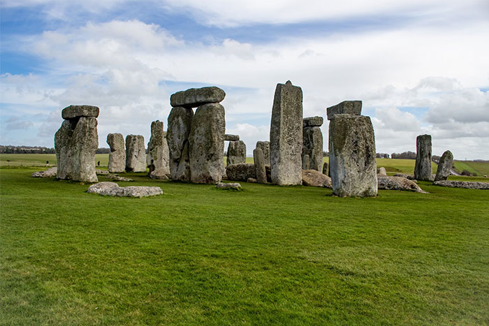 Ancient Stonehenge structure on a grassy field, symbolizing historical collective madness and wasted resources.