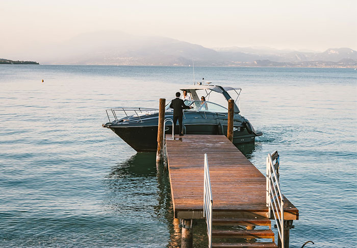 A man stands on a dock next to a luxury boat, illustrating wasted money on extravagant purchases.