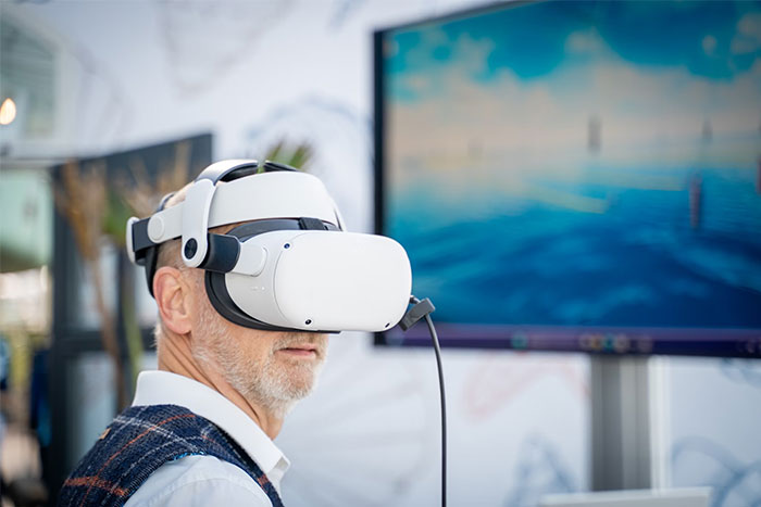 Man using VR headset in a tech expo, showcasing modern advancements and potential waste in technology investments.