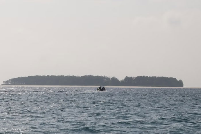 Ocean view with small boat near an isolated island, depicting a scene of wasted potential and unused resources.