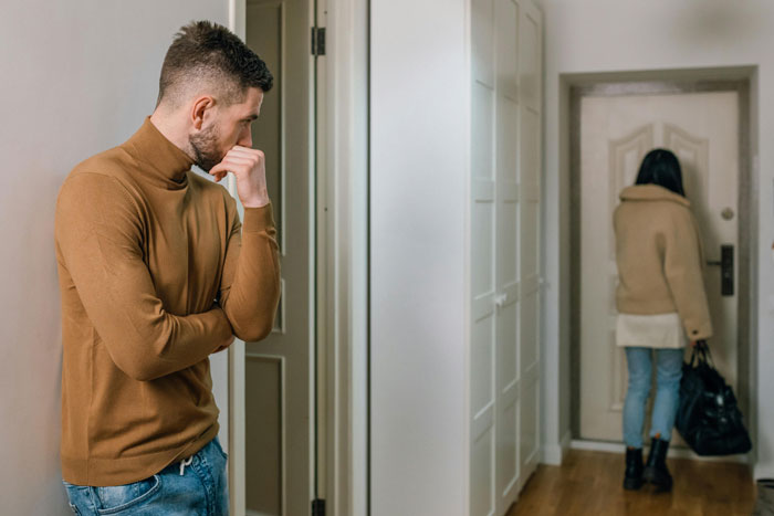 Man in a brown sweater looking concerned as a woman leaves through a door; wedding dress shopping drama.