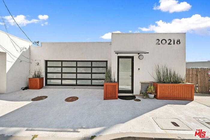 Modern house exterior in Los Angeles with minimalist design and large garage door, featuring the number 20218.