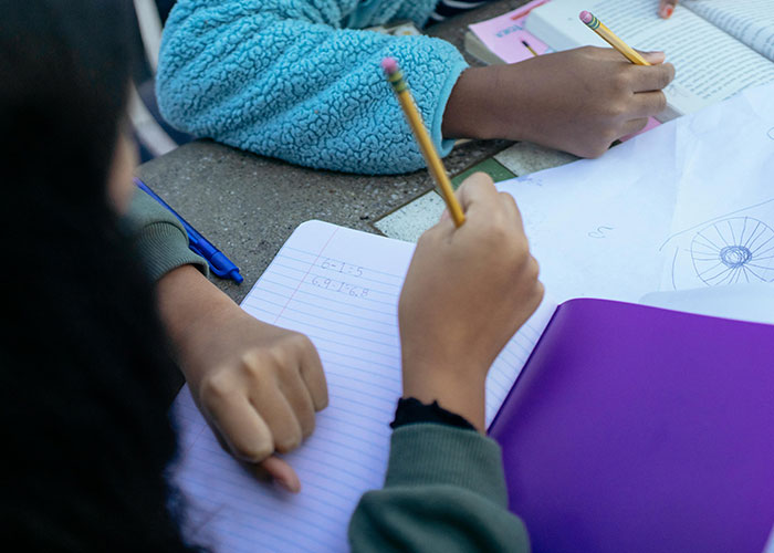 People writing in notebooks at a table, discussing unsolved mysteries.