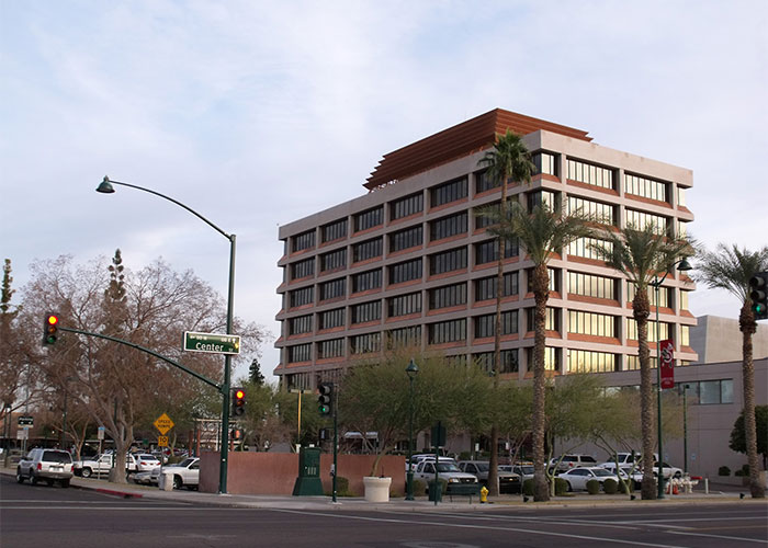 Street view with a modern building, surrounded by palm trees, related to unsolved mysteries from different countries.