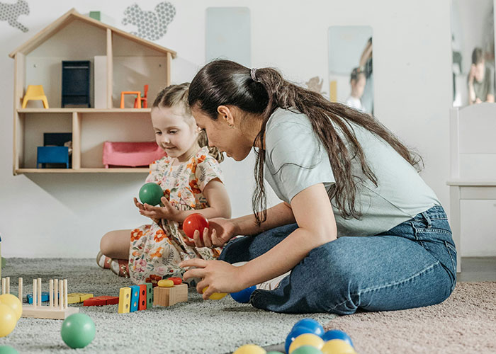 Woman and child playing with colorful balls in a playroom, symbolizing sharing stories about unsolved mysteries.