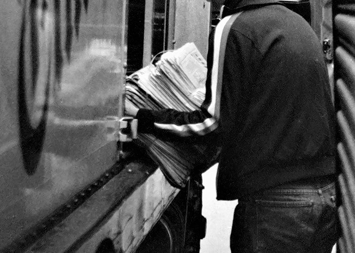 A person in a jacket unloading newspapers from a truck, representing unsolved mysteries coverage.