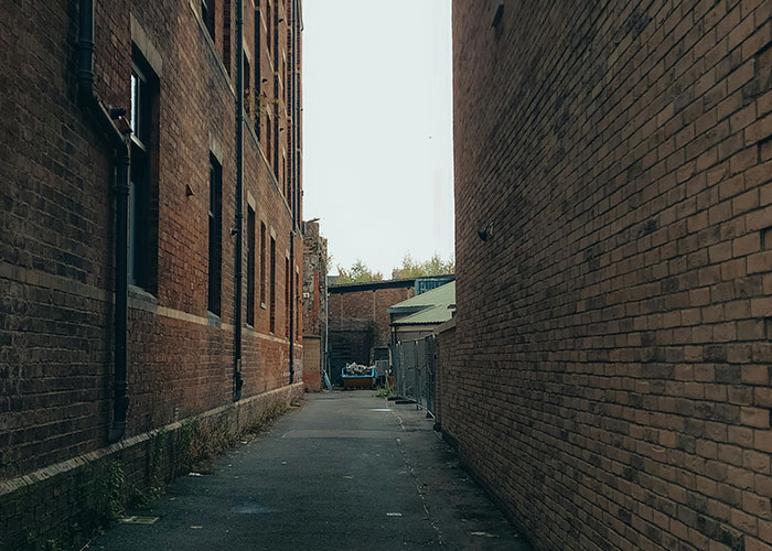 Narrow alleyway with brick buildings, potentially linked to unsolved mysteries, creates a mysterious urban atmosphere.