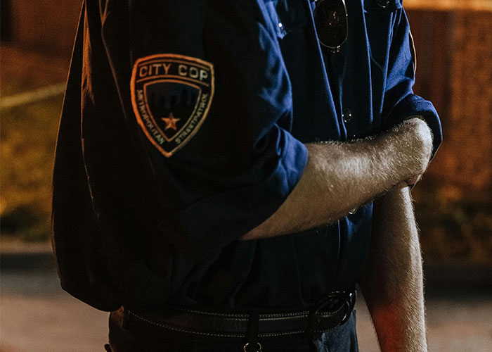 Police officer with arms crossed, wearing a city cop uniform at night, symbolizing unsolved mysteries.