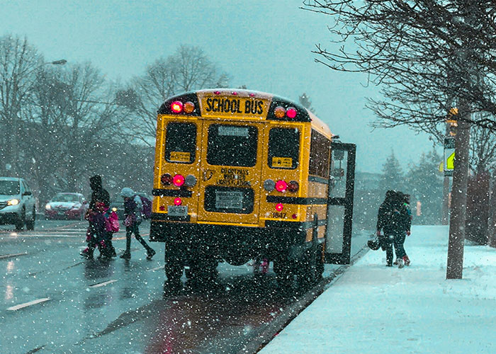 Yellow school bus on snowy road, children crossing; represents unsolved mysteries theme.