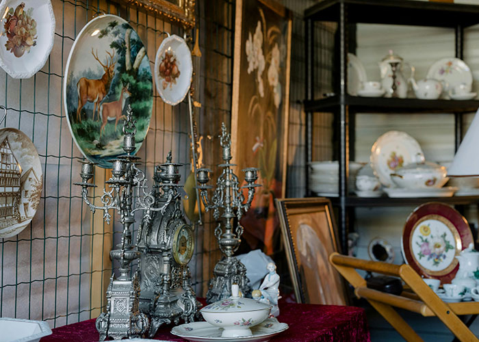 Antique collection with ornate silver candelabras and decorative plates, related to unsolved mysteries from various countries.