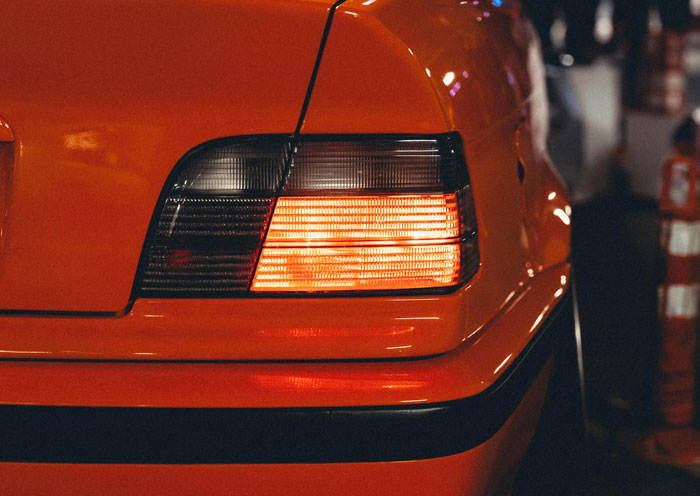 Close-up of a black van with glowing rear lights on a driveway at night.