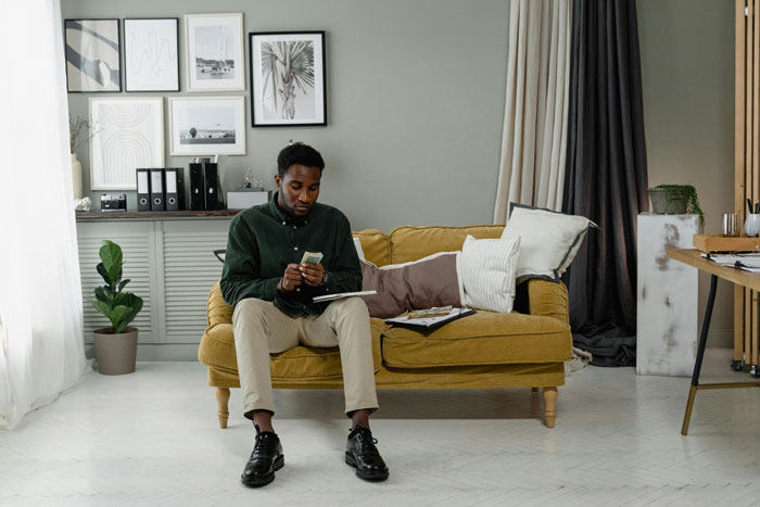 Man looking upset about mortgage payments while sitting on a sofa in a well-decorated living room.