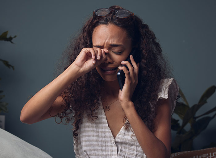 Woman crying on phone after not being invited to best friend's wedding.