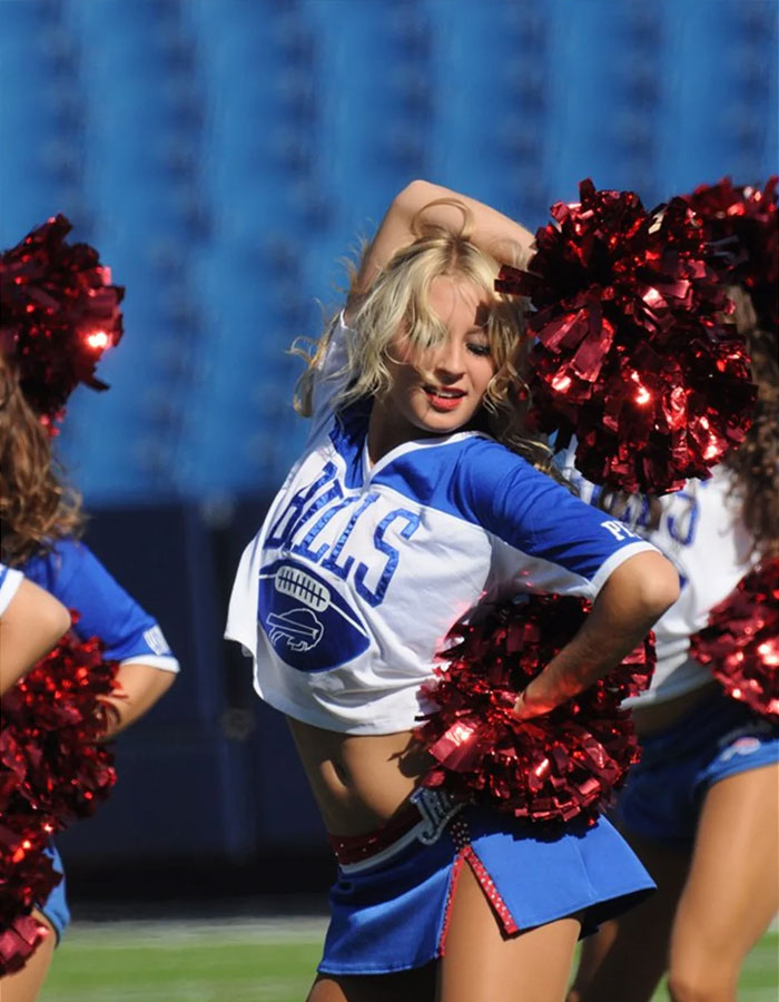 Buffalo Bills cheerleader performing a routine in uniform on the field.