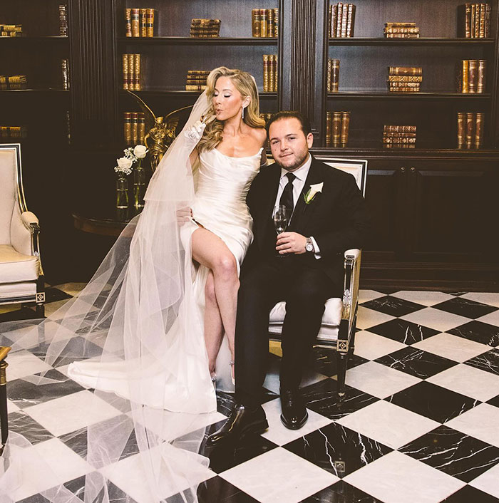 Bride and groom in elegant setting, with library bookshelves in background, celebrating their wedding day.