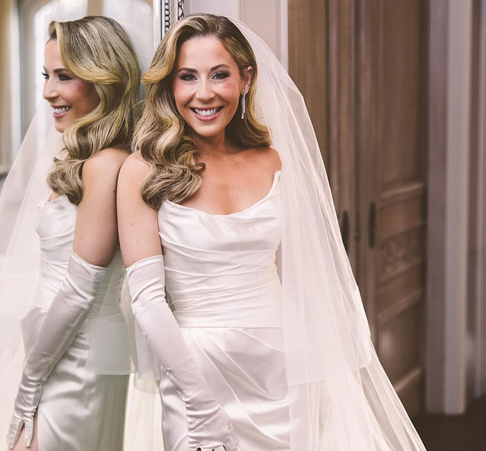 Blonde woman in wedding dress smiling at the mirror, capturing a School of Rock star moment.