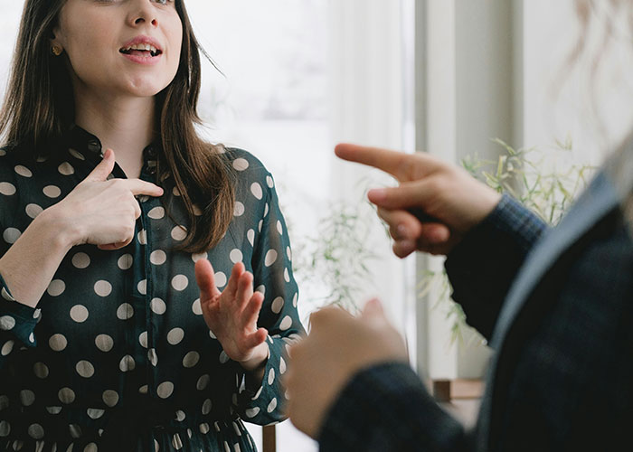 People in discussion, one wearing polka dots, gesturing while talking about university importance.