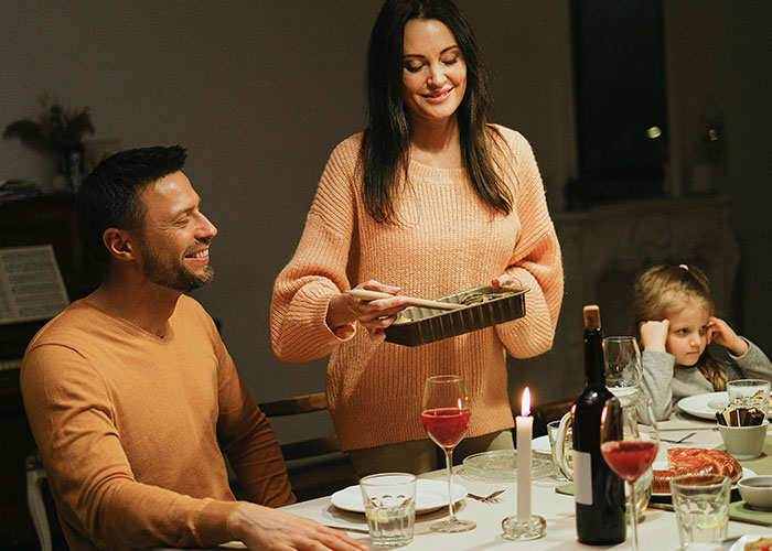 Family dinner conversation about university with food, wine, and a child looking bored.