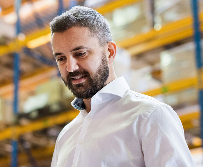 Man in a warehouse, embodying retail workers' unique stories, wearing a white shirt.