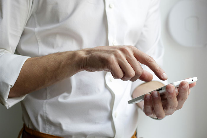 Retail worker in a white shirt using a smartphone, possibly sharing an unbelievable story.