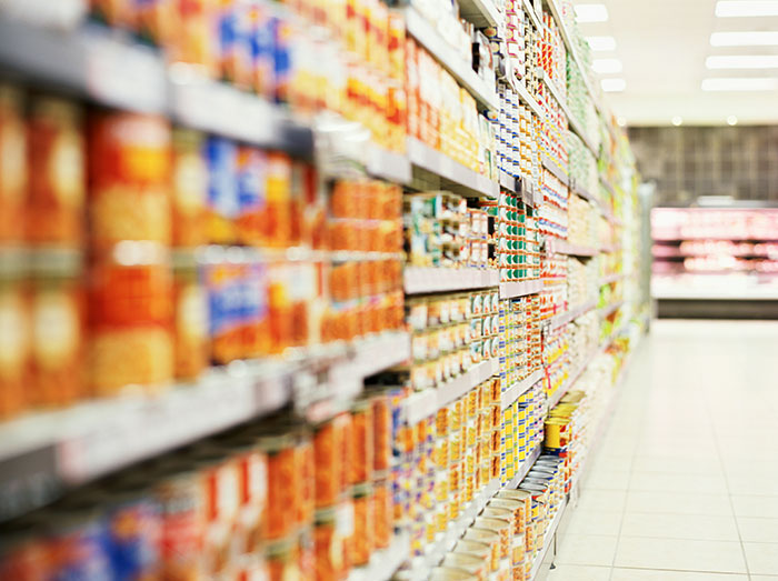 Retail workers' stories unfold in a colorful grocery store aisle filled with neatly stocked products.