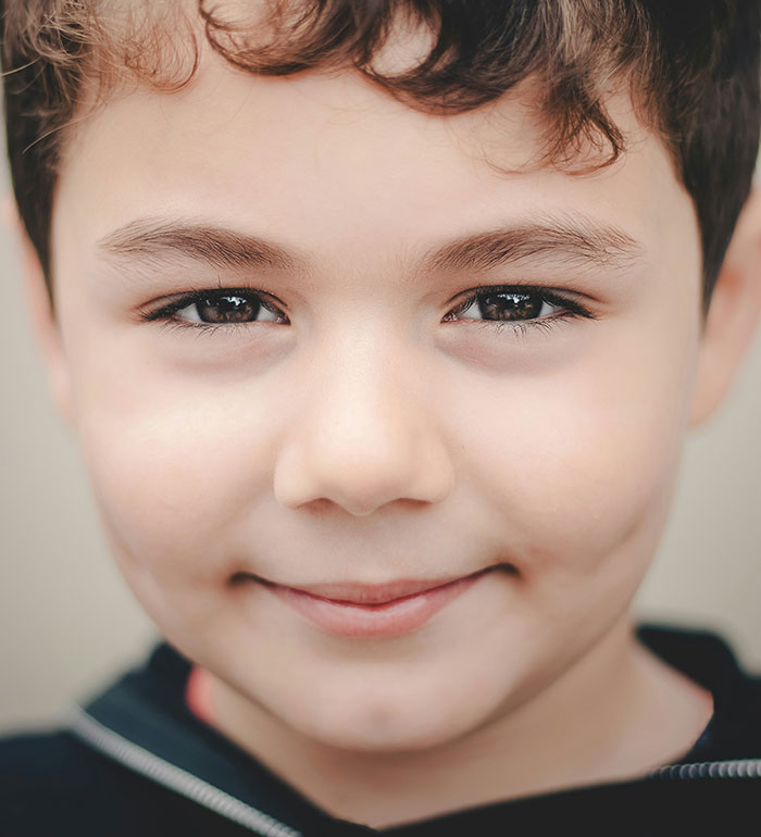 Boy smiling warmly, the concept of incredulous stories in retail highlighted through a childlike perspective.