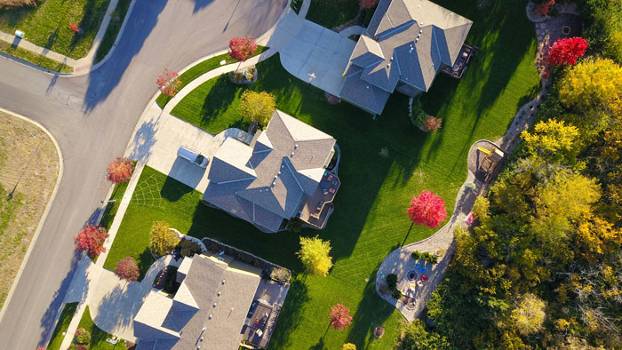 Aerial view of houses in a neighborhood with cars parked in driveways.